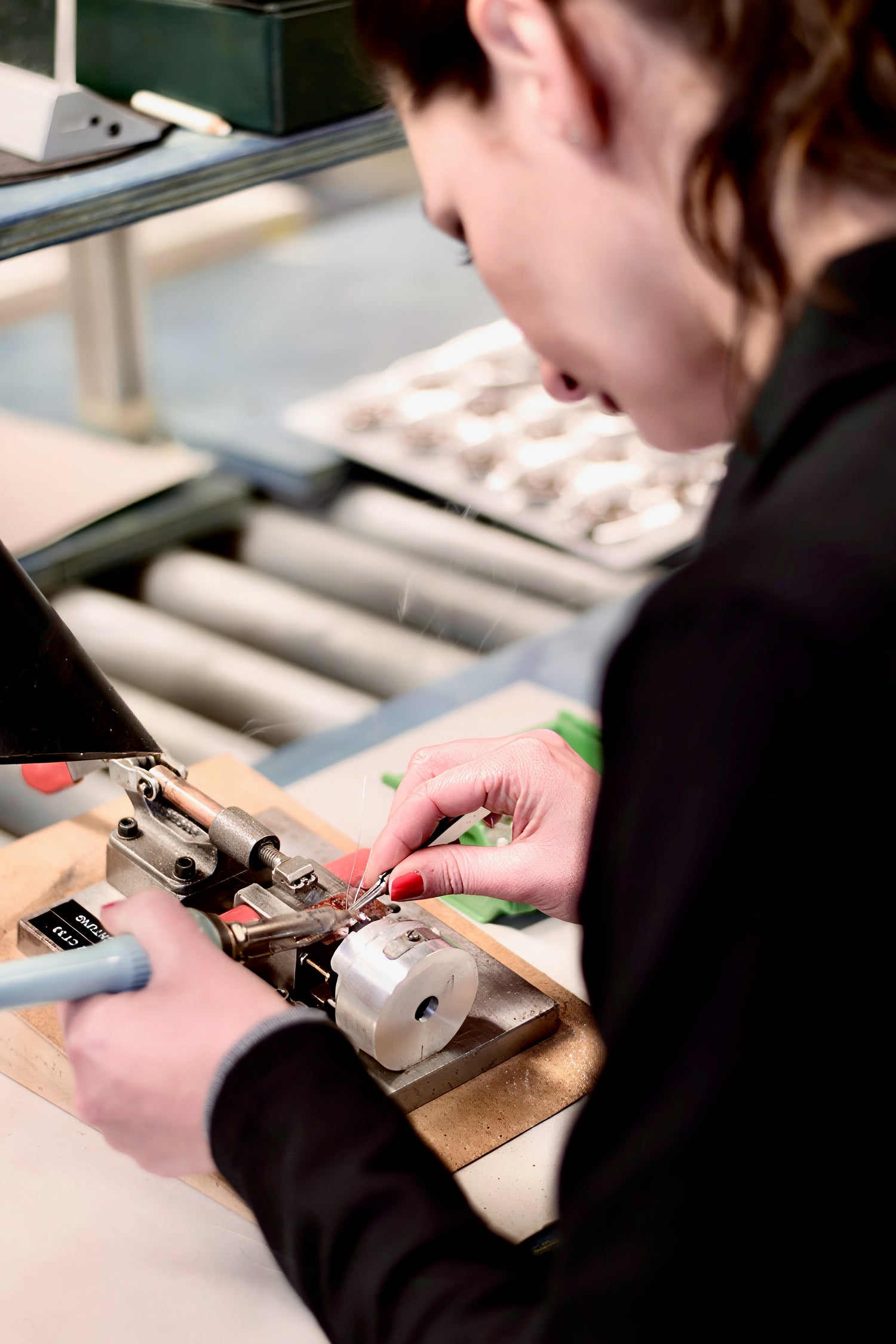 A skilled technician at the German Maestro factory meticulously assembles a tweeter by hand, using precision tools to work on the intricate components at her workbench.